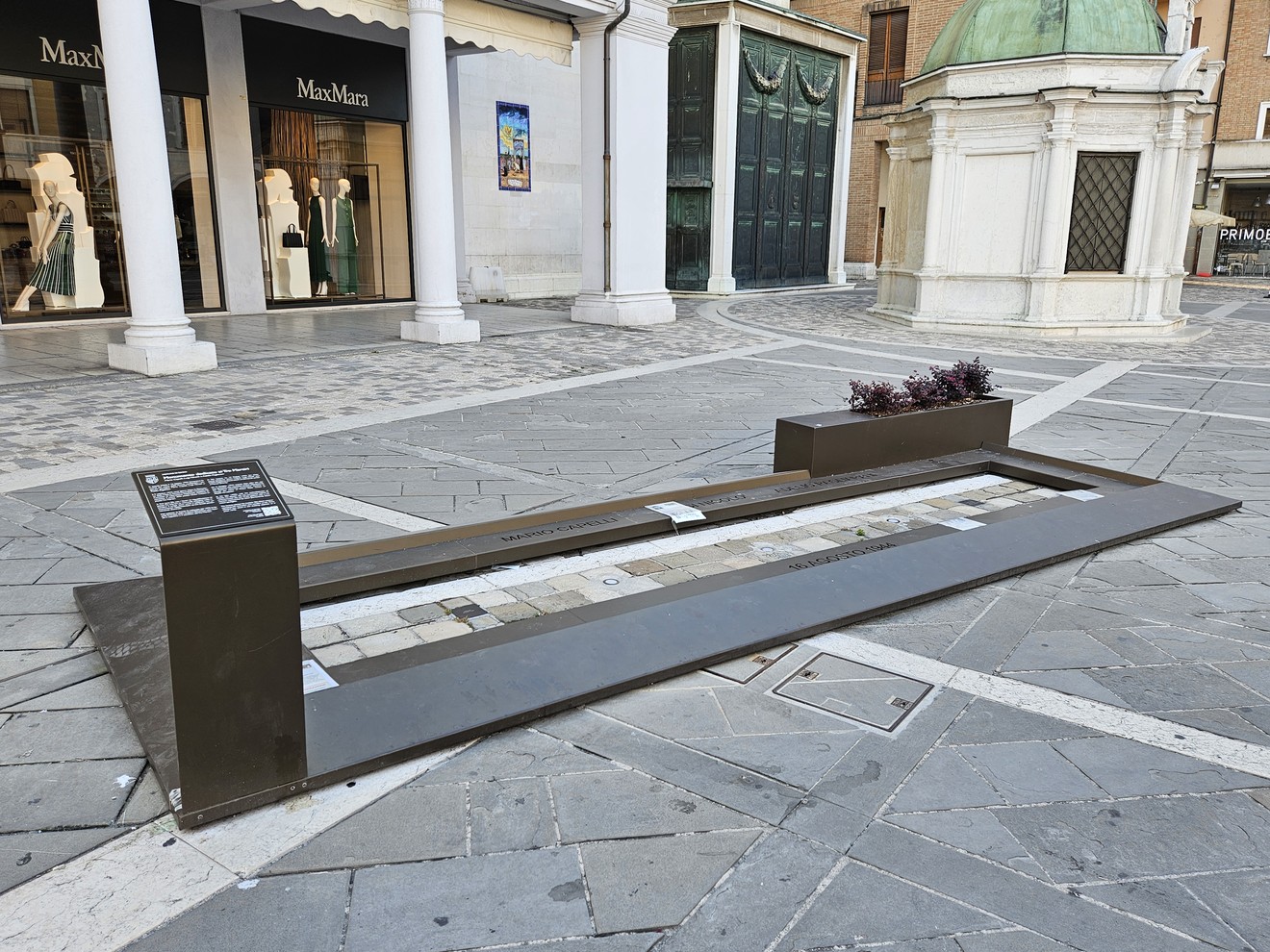 Monumento ai Tre Martiri, una lastra commemorativa in una piazza, dove si distingue il design urbano circostante.