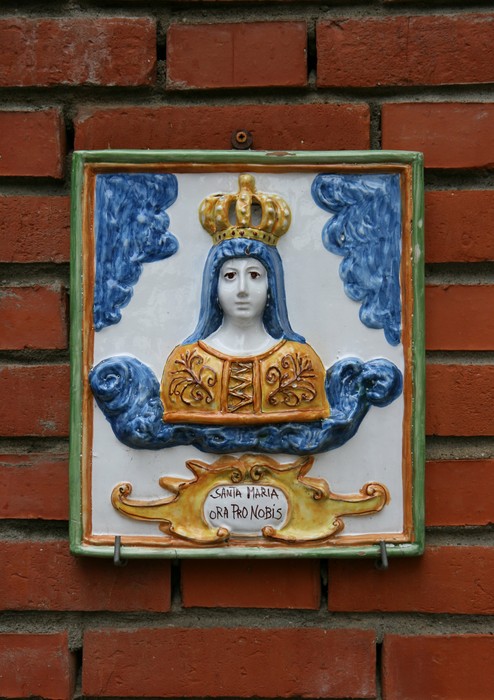 Affresco ceramico che raffigura Santa Maria, collocato sul muro di un edificio.