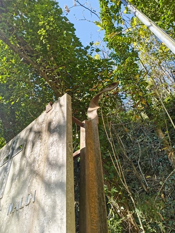 Monumento a Naldi, incastonato nella natura, tra vegetazione rigogliosa e un cielo sereno.