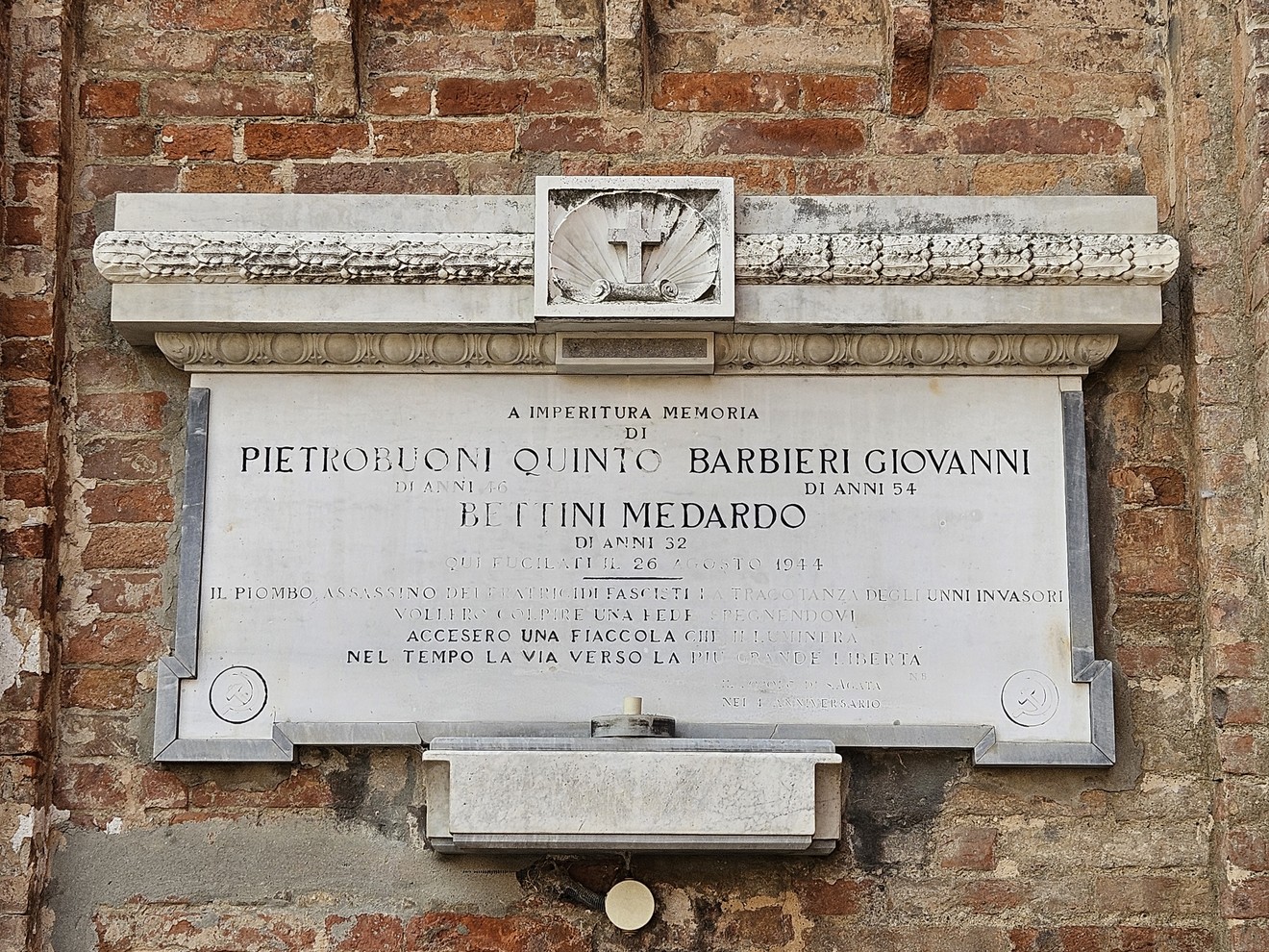 Lapide commemorativa in onore di Pietrobuoni, Barbieri e Bettini, incastonata in un muro di mattoni.