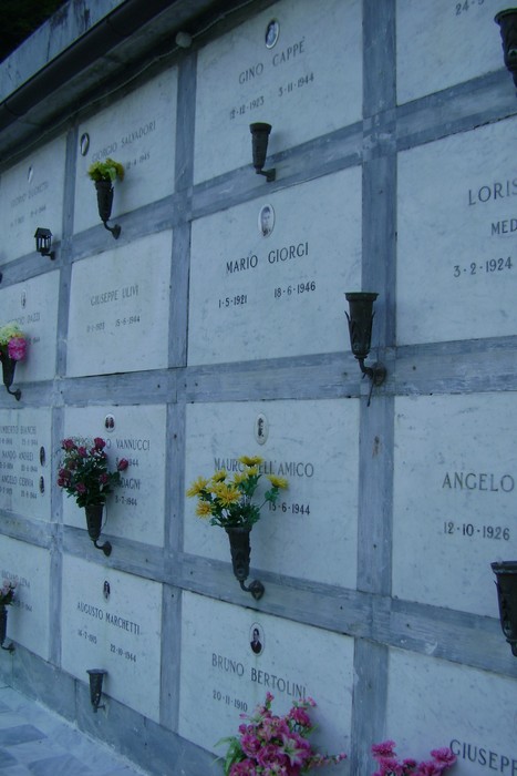 Sepolcri commemorativi dei caduti per la libertà, con lapidi e fiori.