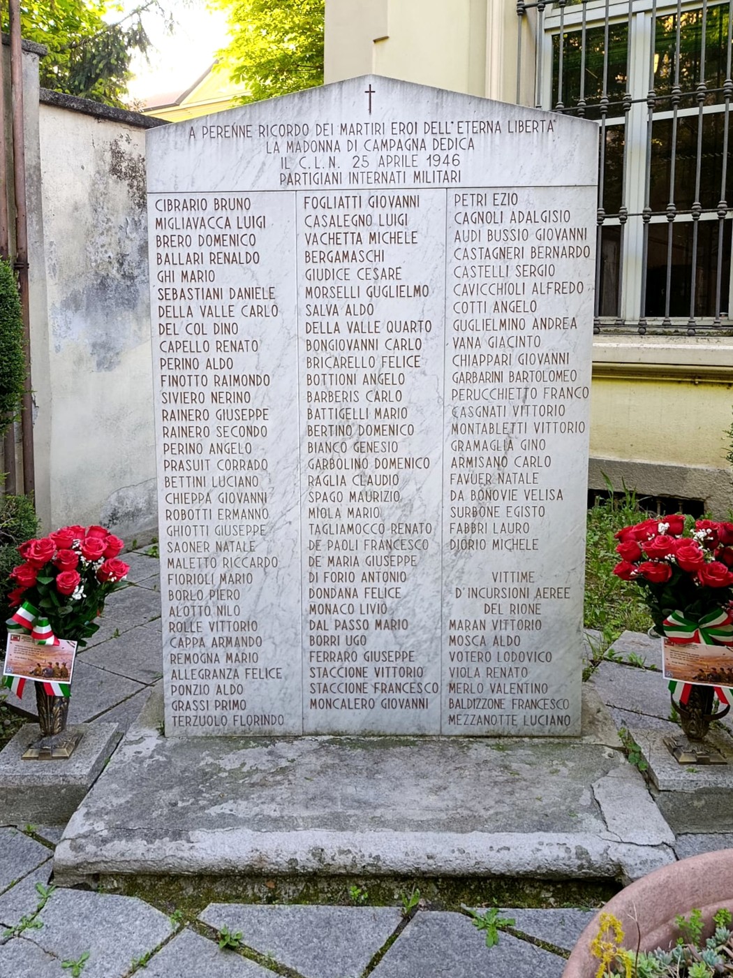 Monumento dedicato ai Martiri della Libertà, Madonna di Campagna, circondato da fiori e con iscrizioni commemorative.