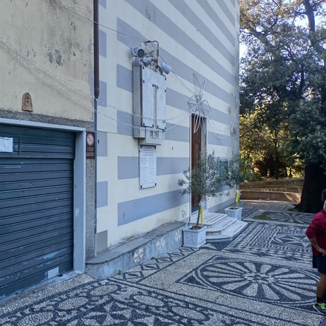 Lapide commemorativa ai caduti, collocata su una parete in un contesto urbano, circondata da un pavimento decorativo.