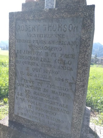 Cippo commemorativo dedicato a Robert Thomson, pilota americano, in un contesto naturale sereno.