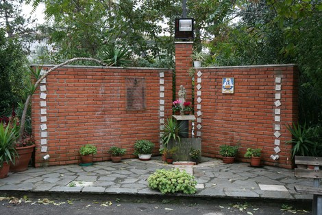 Monumento dell'Indicatore: un memoriale circondato da piante, mattoni e decorazioni che evoca riflessione e memoria.