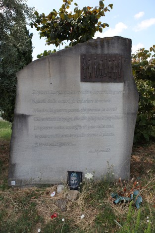 Monumento commemorativo in pietra dedicato all'eccidio di Pratomaggiore, con simboli e decorazioni.