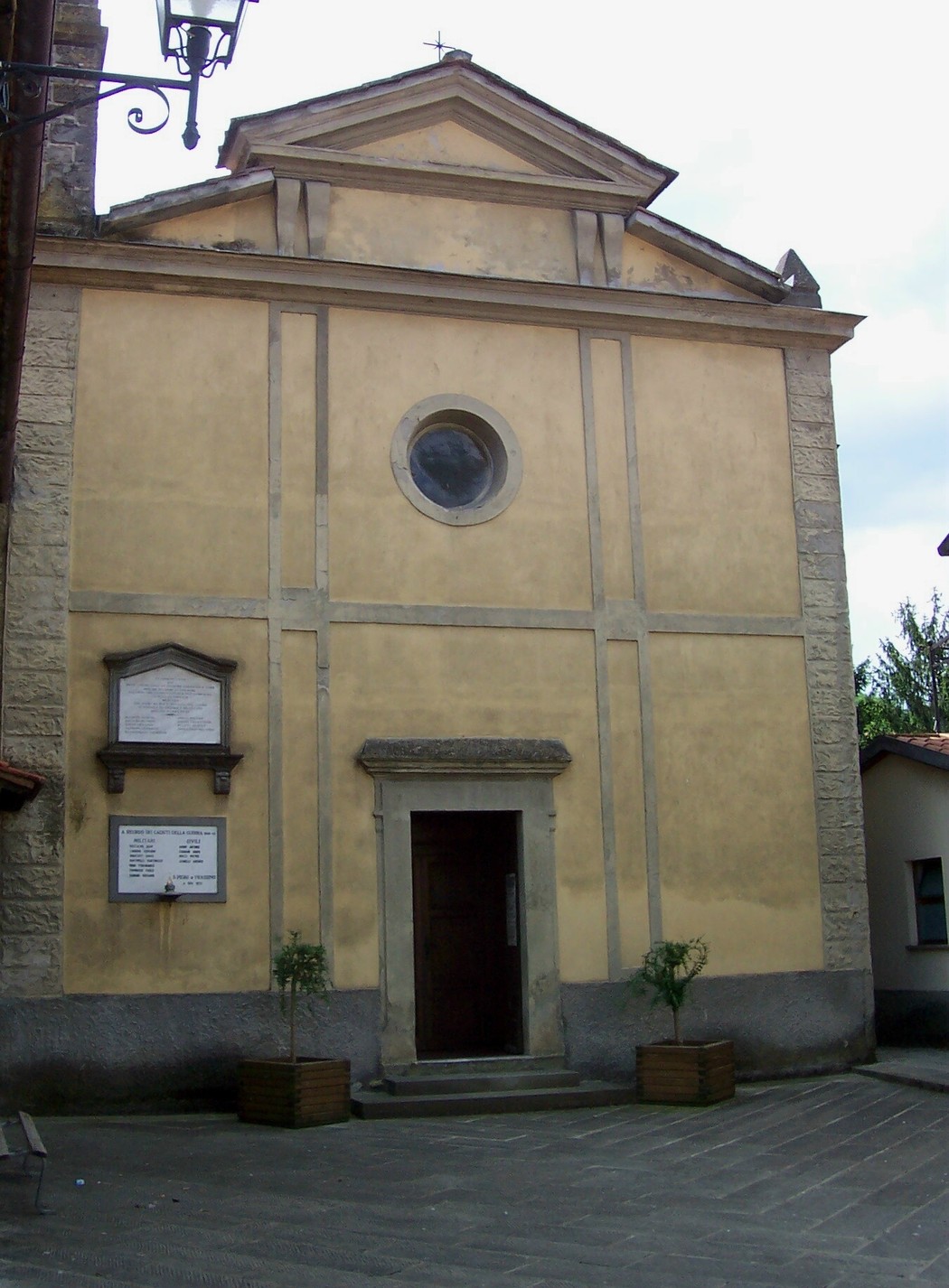 Lapide commemorativa dei caduti di San Piero, situata accanto alla chiesa del paese, in un contesto storico e culturale.