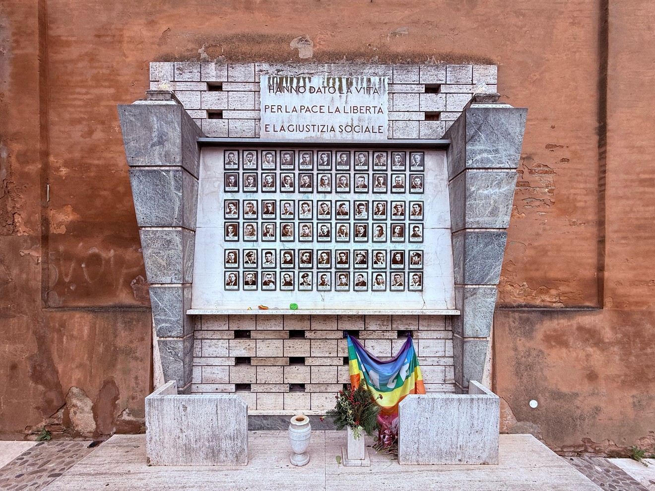 Sacrario dei caduti partigiani, monumento commemorativo con foto e fiori, simboleggia pace e libertà.