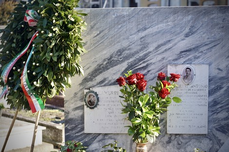 Sepolcri con decorazioni floreali, lapidi e un omaggio commemorativo in un cimitero.