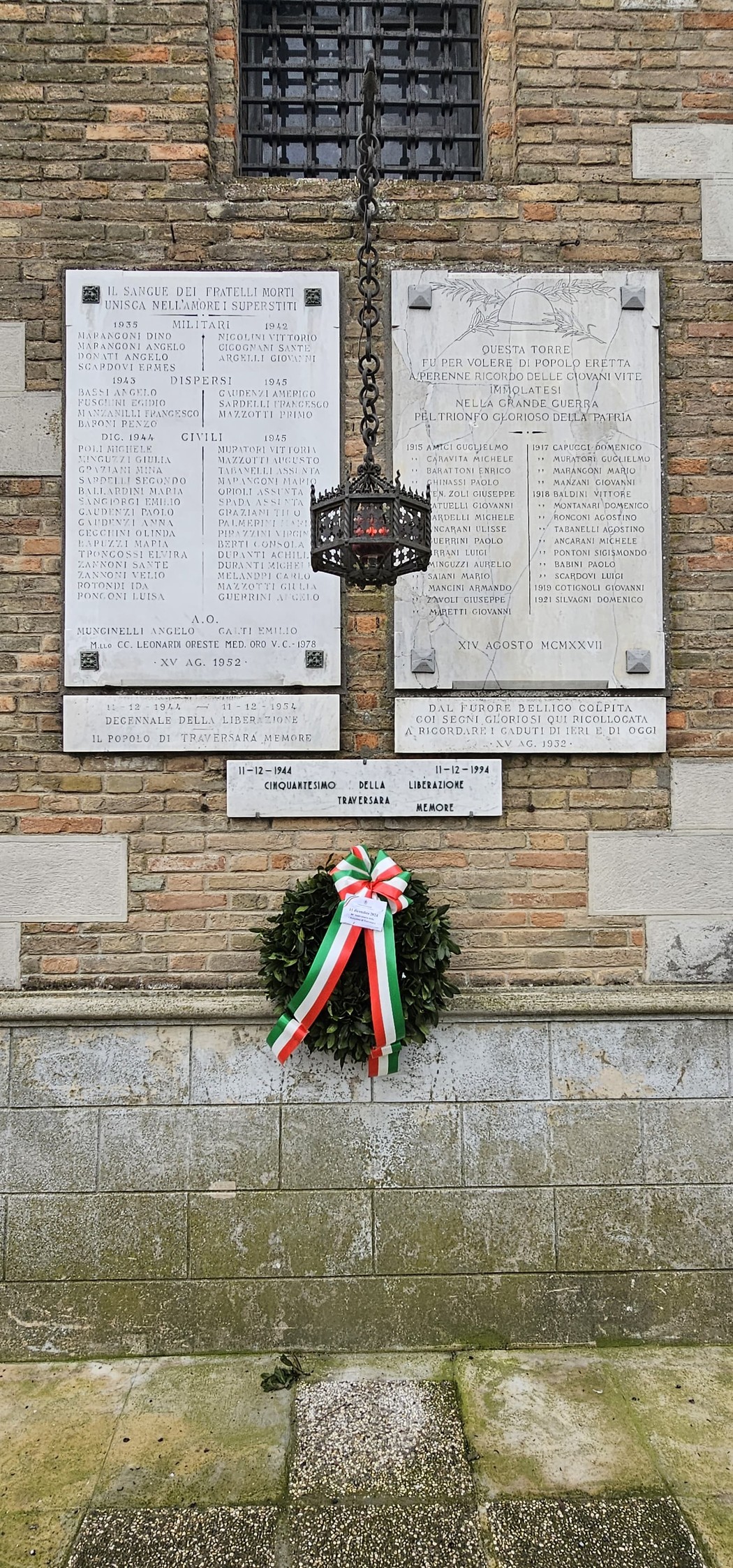 Lapidi commemorative ai caduti di Traversara, con una corona di alloro e un'atmosfera di rispetto e memoria.