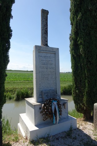 Monumento a Gennaro con decorazioni floreali, immerso in un paesaggio rurale.
