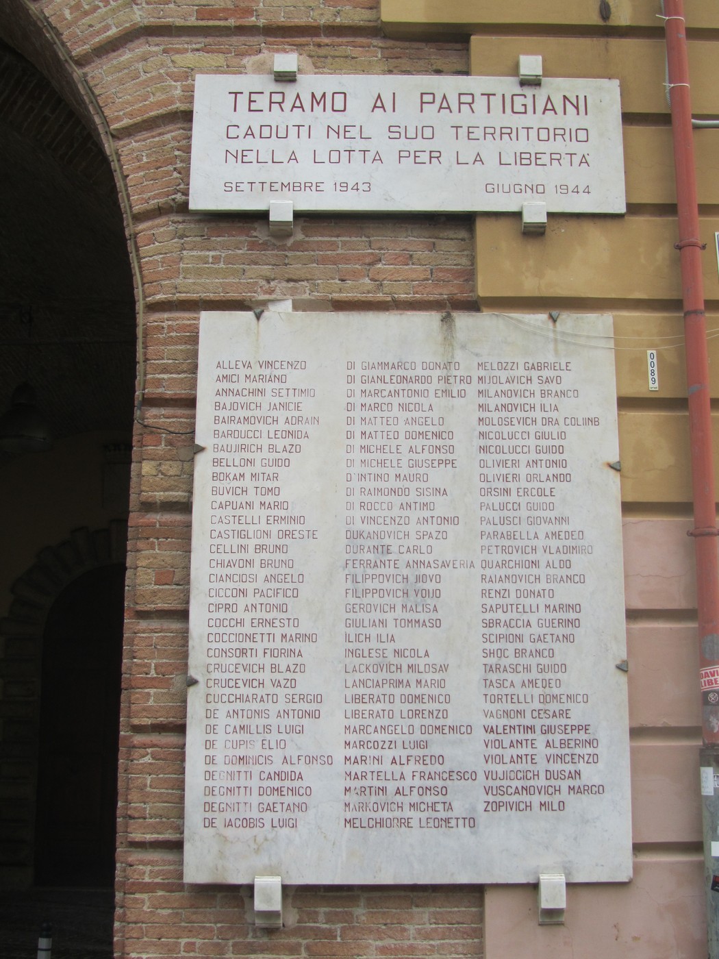 Lapide commemorativa ai partigiani caduti nel teramano, con nomi e date di riferimento.