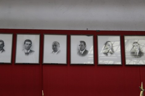 Monumento commemorativo con ritratti in bianco e nero di caduti dell'Ansaldo Elettrotecnico su sfondo rosso.