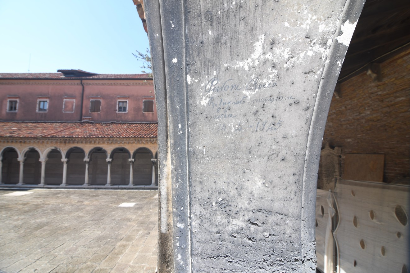Iscrizione su un muro in un contesto storico, evocando la memoria di rifugiati dai bombardamenti.