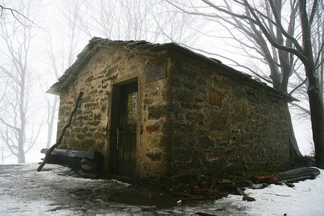 Lapide del Capanno dei Partigiani, rifugio storico immerso nella nebbia e nella natura.