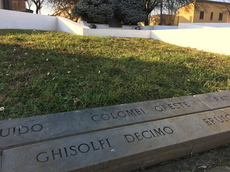 Monumento ai caduti di Travacò Siccomario, con un'area verde e iscrizioni commemorative su una stele.