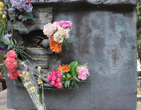 Monumento ai deportati, con fiori colorati posati su una superficie metallica in memoria delle vittime.