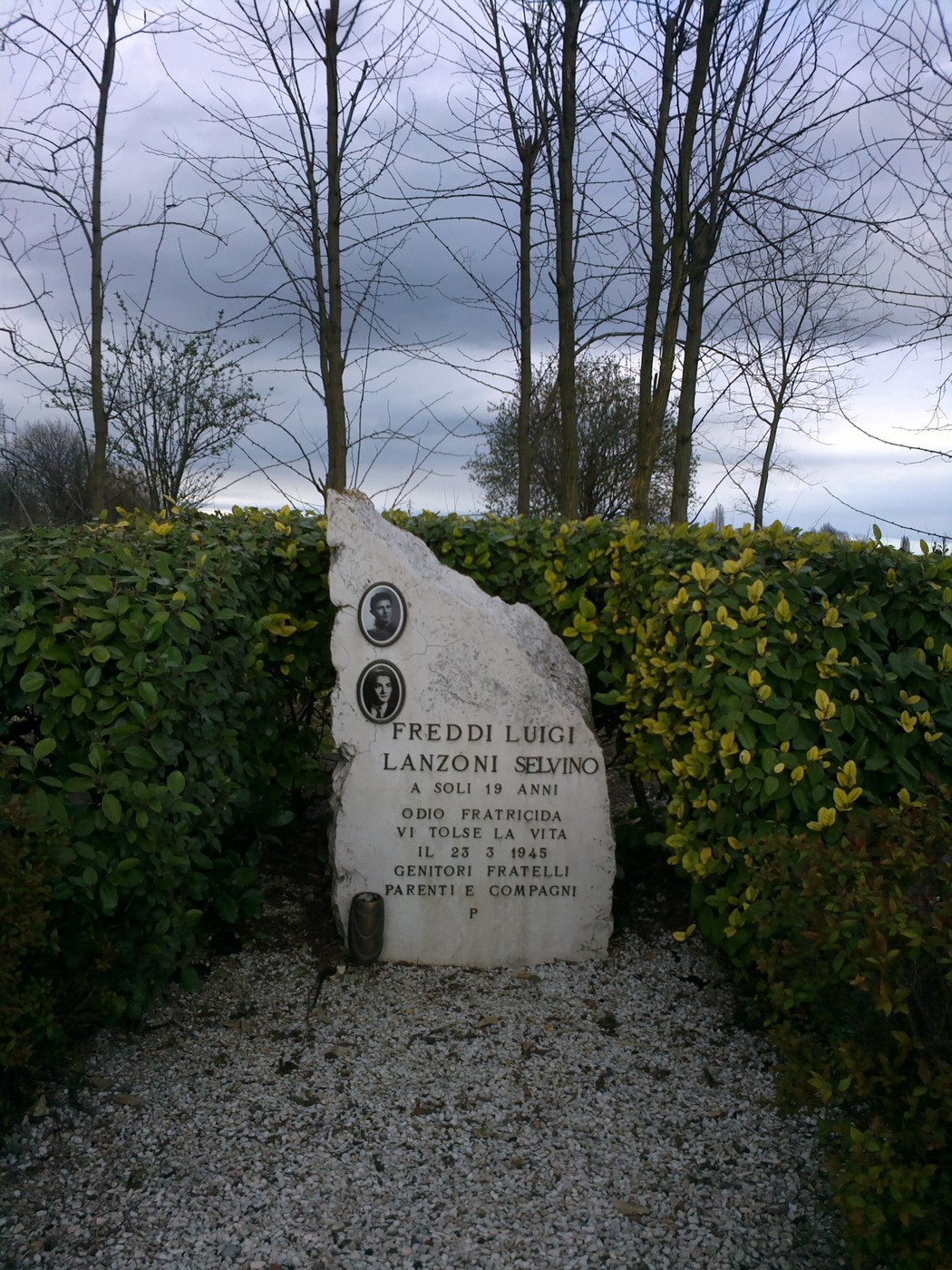 Monumento commemorativo a Freddi e Lanzoni, situato in un area verde con alberi e cespugli.