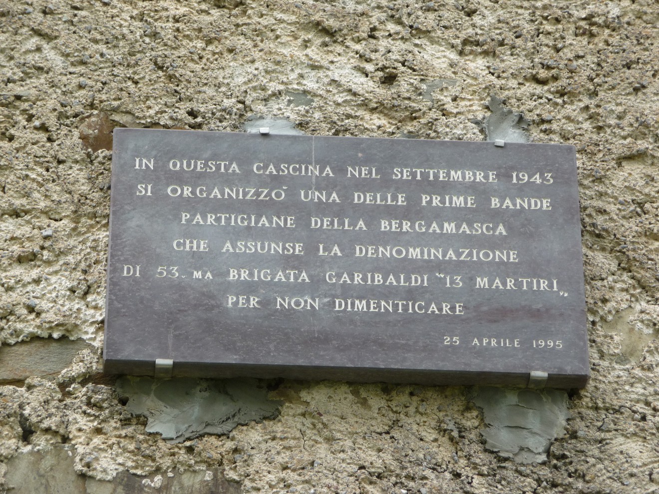 Lapide commemorativa della 53a brigata Garibaldi, dedicata alla memoria dei partigiani. Resti storici in un contesto rurale.