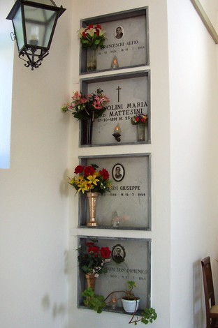 Cappella dedicata ai caduti partigiani, con loculi commemorativi adornati di fiori e luci.