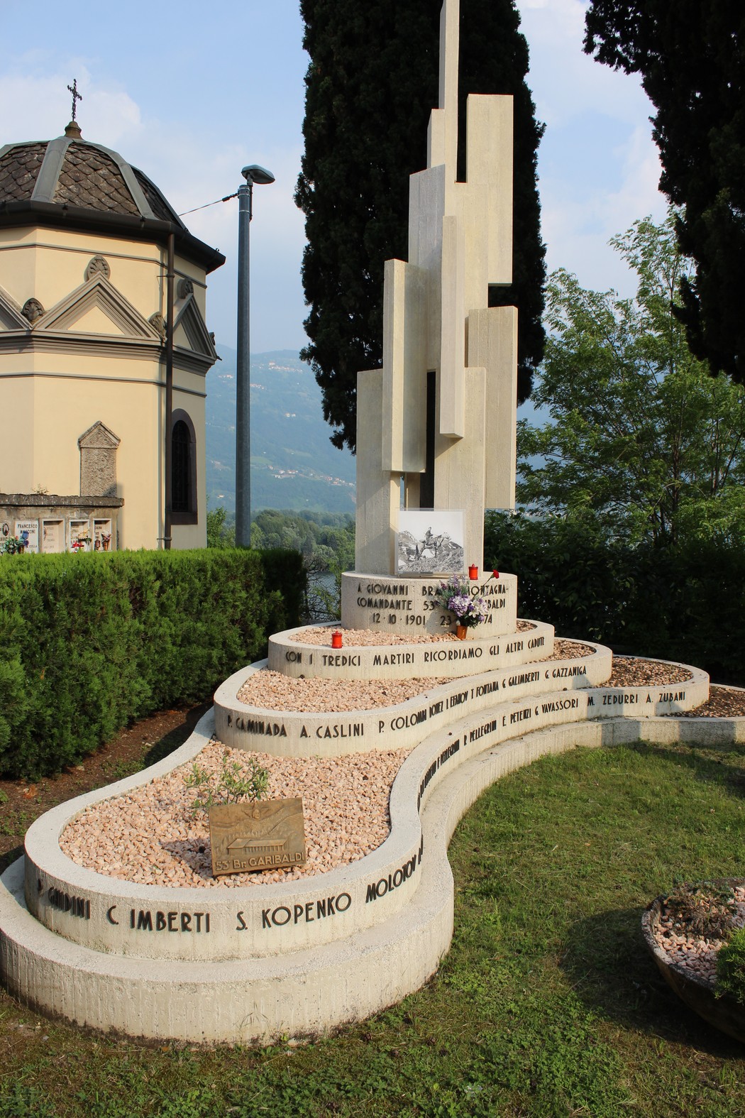 Sacrario alla 53a Brigata Garibaldi, un monumento commemorativo tra vegetazione e un cielo sereno.