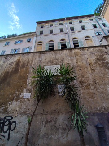 Lapide commemorativa che ricorda il genocidio dei nomadi, affissa su un muro di un edificio storico.