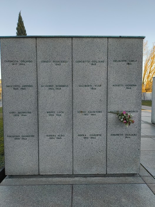Monumento commemorativo al "Campo della Gloria" con lapidi in pietra e fiori freschi.