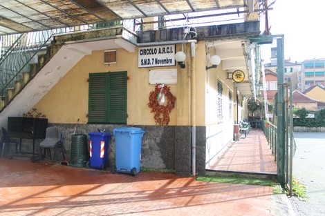 L'ingresso del Circolo A.R.C.I. con decorazioni e bidoni per la raccolta differenziata. Ambiente esterno curato.