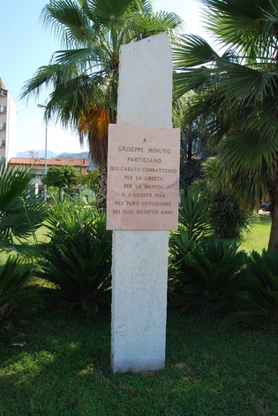 Cippo commemorativo dedicato a Giuseppe Minuto, partigiano per la libertà, situato in un giardino pubblico.