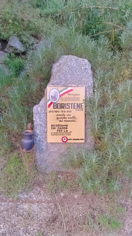 Cippo commemorativo a Boristene, con testo informativo su un evento storico e circondato da vegetazione.