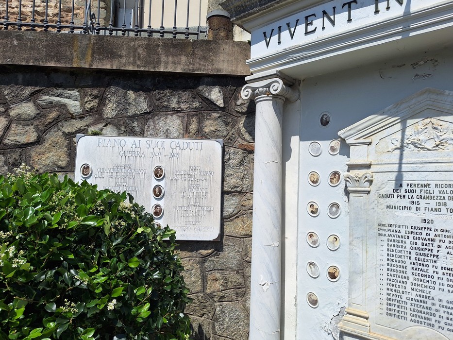 Lapide commemorativa ai caduti, con monumento e targhe in memoria. Pannelli in pietra e dettagli architettonici.