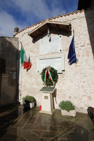 Lapidi commemorative in memoria dell'eccidio di Mucciafora, con decorazioni e bandiere.
