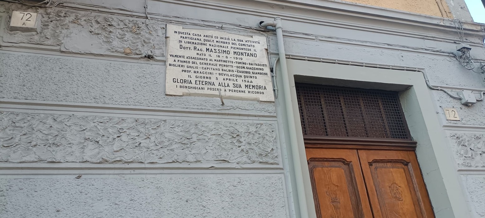 Lapide commemorativa dedicata a Massimo Montano, situata su una facciata di edificio storico.