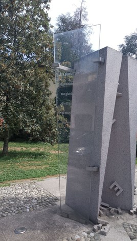 Monumento alla Resistenza, struttura moderna in pietra con dettagli trasparenti e ambiente verde circostante.