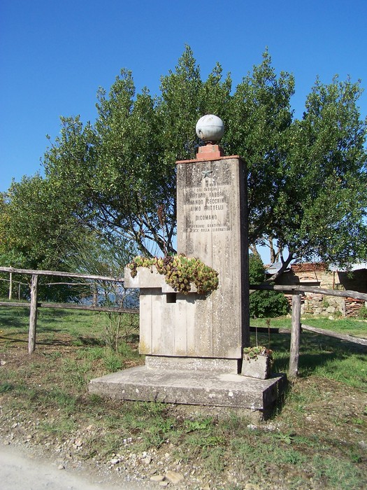 Cippo di Santa Lucia, monumento in pietra circondato da verde, evocativo della tradizione locale.