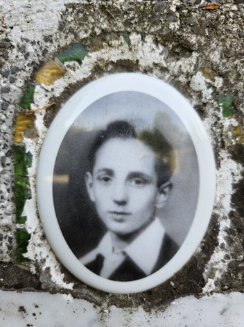 Ritratto in bianco e nero di un giovane, incastonato in una cornice ovalizzata, su un cippo di Gualdi.