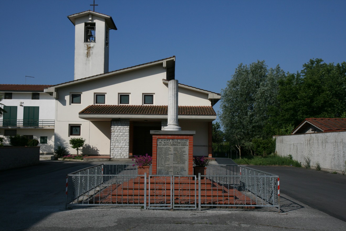 Cippo commemorativo di Anchione, con la chiesa sullo sfondo e un recinto di protezione attorno al monumento.