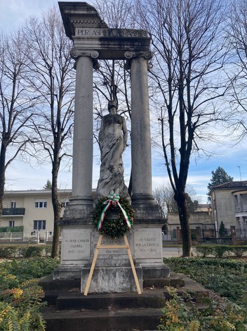 Monumento ai Caduti di Castel Goffredo, con colonnato e statua, circondato da piante e alberi.