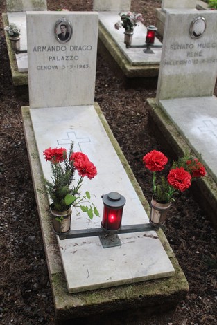 Tombe con fiori e lumini dedicati ai caduti per la Libertà, in un ambiente di commemorazione e rispetto.