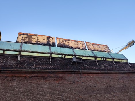 Pannelli artistici sui muri del carcere Le Nuove, raffiguranti volti di imprigionati.