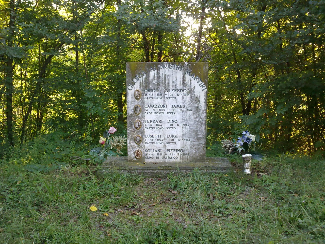 Monumento commemorativo dedicato a Orioli e ad altri caduti, immerso nella natura.
