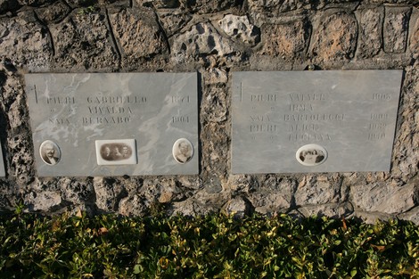 Ossario di Sant'Anna di Stazzema con lapidi commemorative e fotografie in un contesto di pietra.