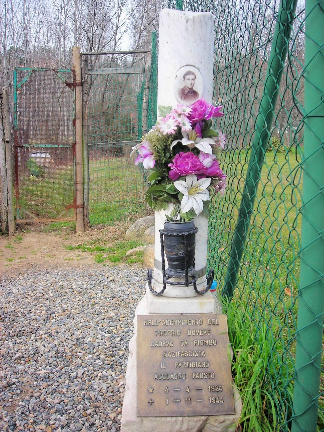 Cippo commemorativo ad Acquadro con fiori, grata e in ricordo di un partigiano.