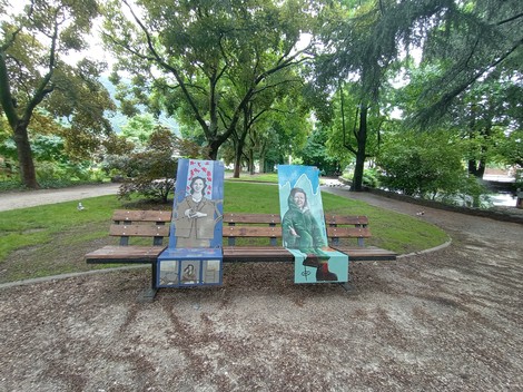 Panchine artistiche nel parco con ritratti colorati di persone su entrambi gli schienali.
