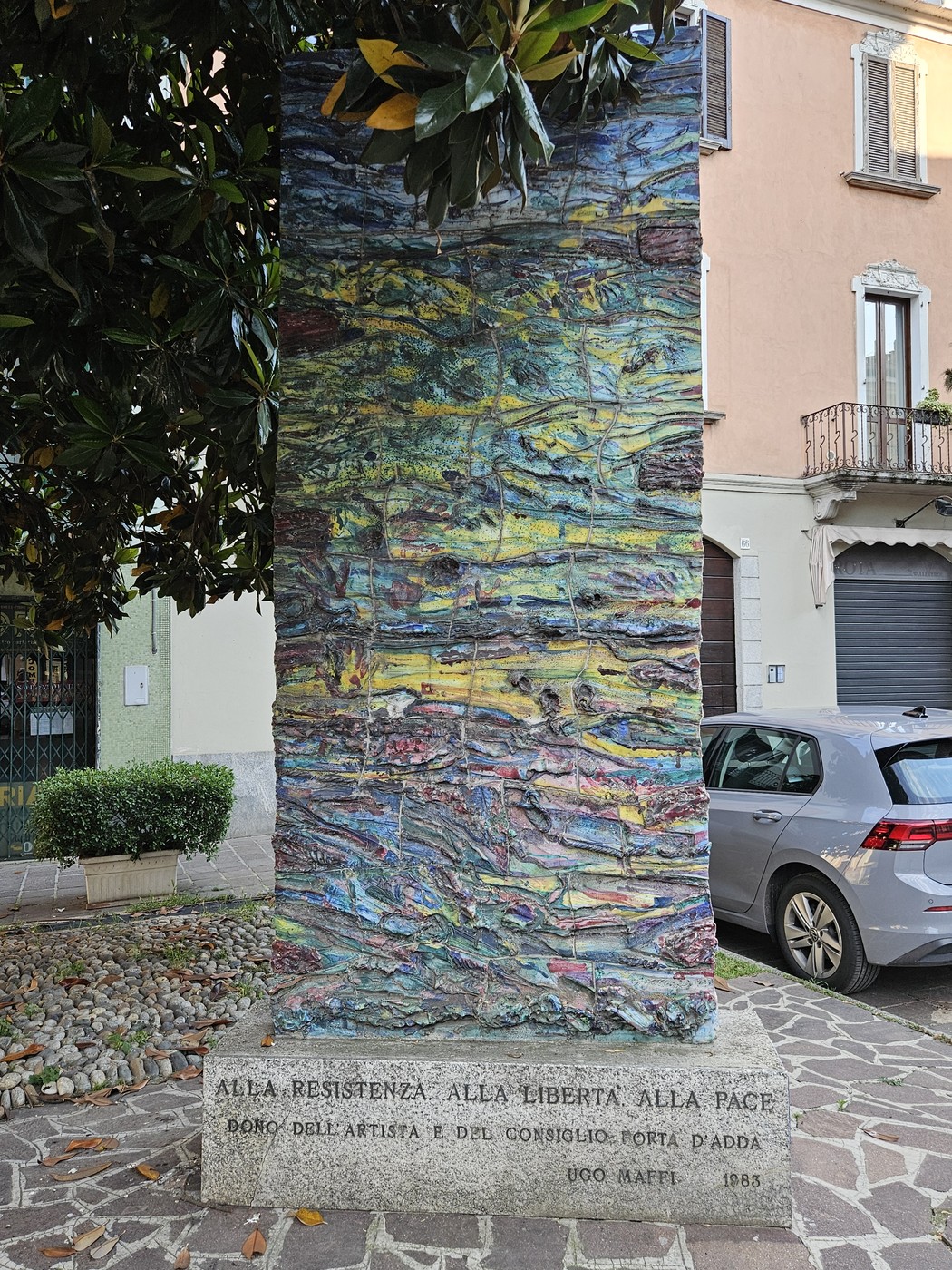 Monumento colorato dedicato alla Resistenza, alla Libertà e alla Pace, circondato da un contesto urbano.