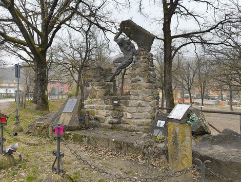 Monumento ai caduti di Botteghino di Zocca, con un’architettura in pietra e statua commemorativa tra alberi.