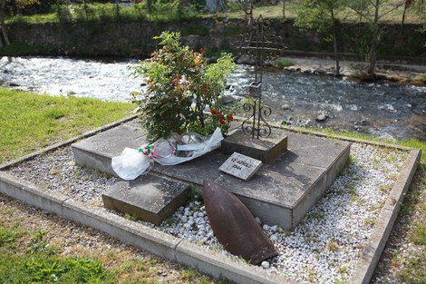 Monumento agli operai fucilati, con un altarino vegetale e un proiettile, immerso in un contesto naturale.