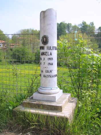 Cippo commemorativo dedicato a Iulitta Angela, situato in un contesto naturale.