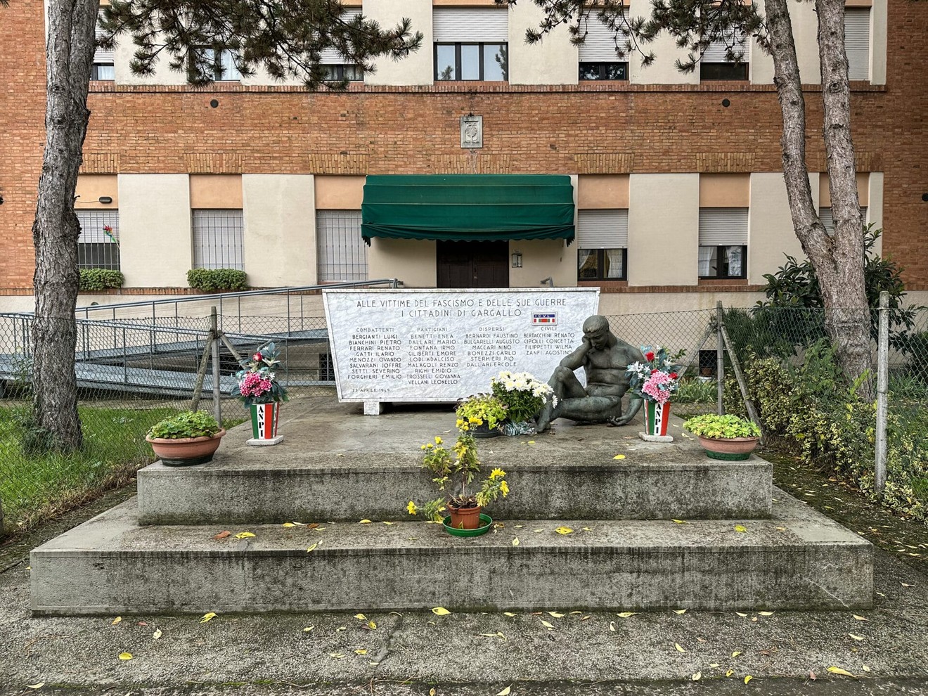 Monumento ai caduti di Gargallo, con fiori e dedica in memoria dei guerrafondatori.