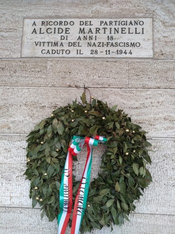Lapide commemorativa di Alcide Martinelli, partigiano vittima del nazifascismo, con coroncina di alloro.